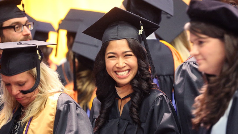 Female student in cap and gown smiling at Commencement