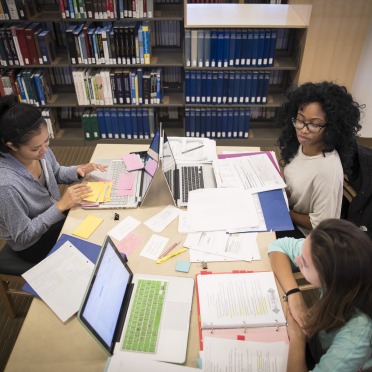 Three students prepare their remarks for a presentation