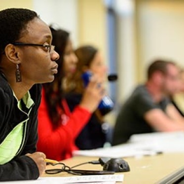 A student sits listening to her professor. 